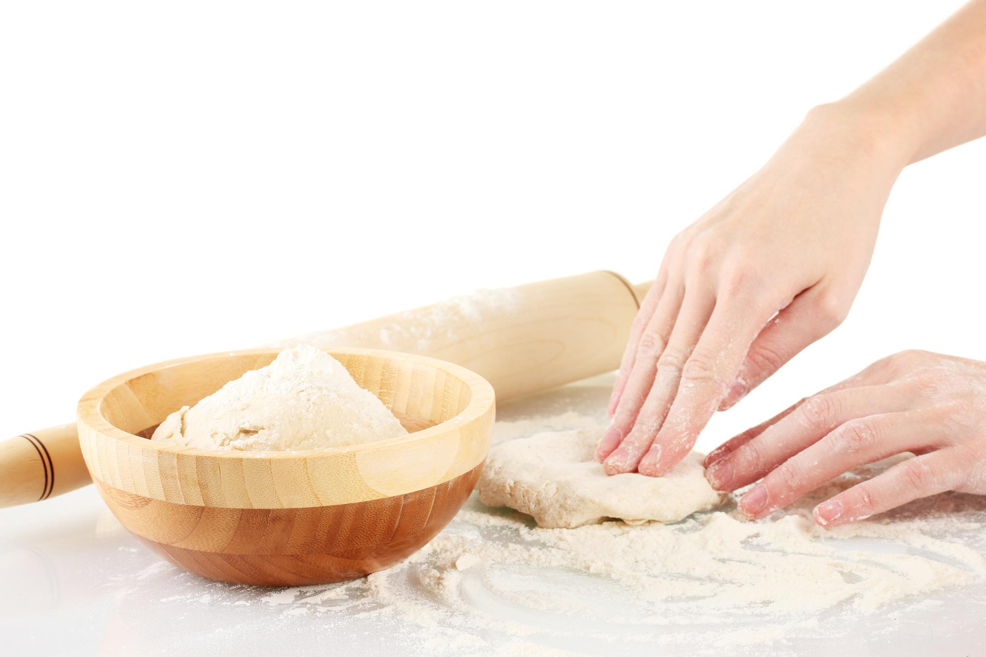 Hands preparing dough on wooden board